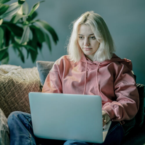 Ung kvinde tager E-Learning kursus fra hendes sofa.
